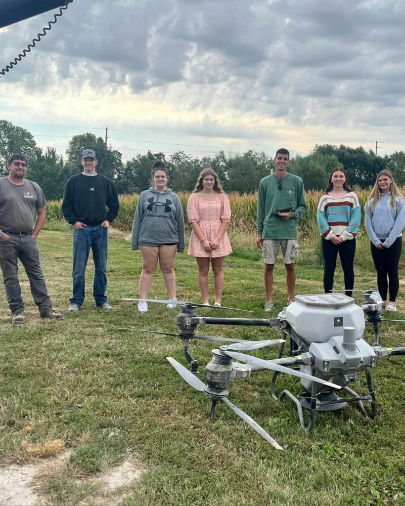 people gathered around a drone for cover crop seeding