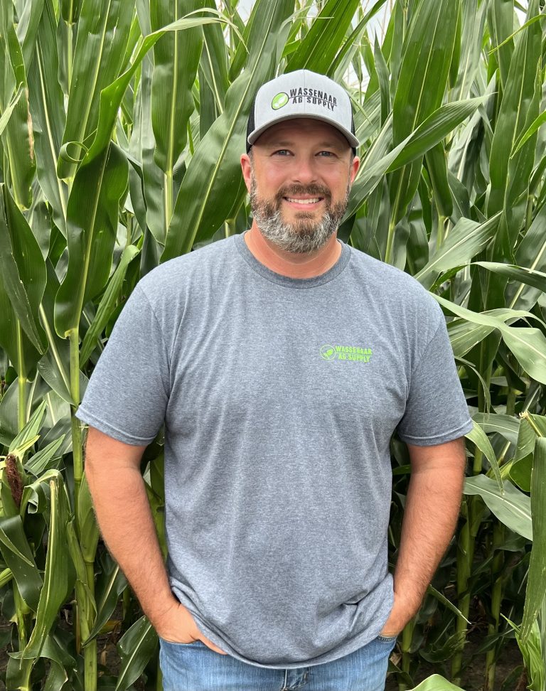 Man wearing baseball hat standing near corn stocks