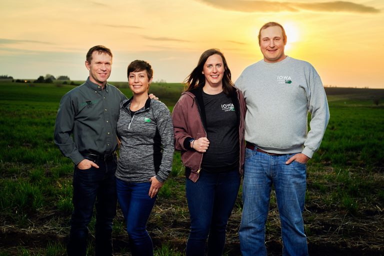 Two couples standing in an iowa farm field with cover crops at sunset